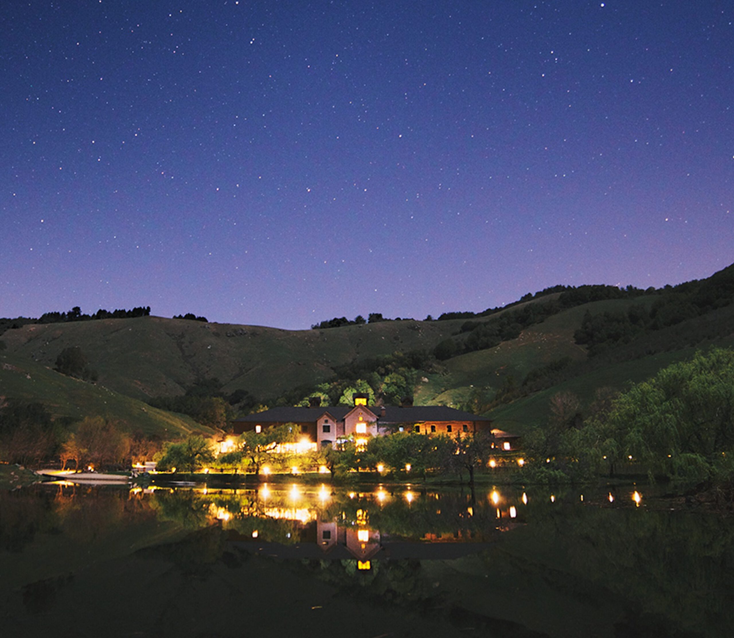 The Technical Building at Skywalker Ranch, illuminated across Lake Ewok under a clear night sky.