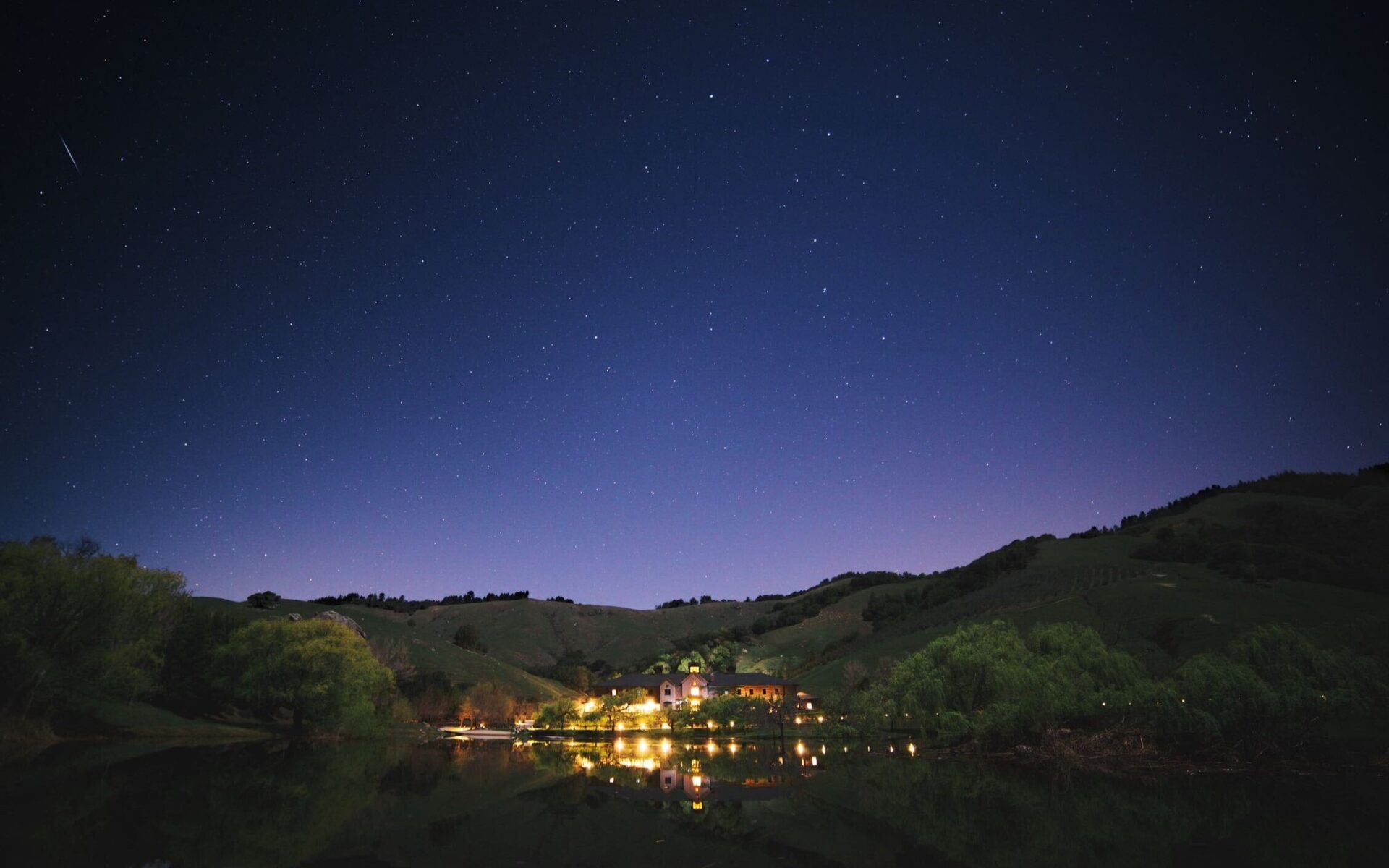 The Technical Building at Skywalker Ranch, illuminated across Lake Ewok under a clear night sky.