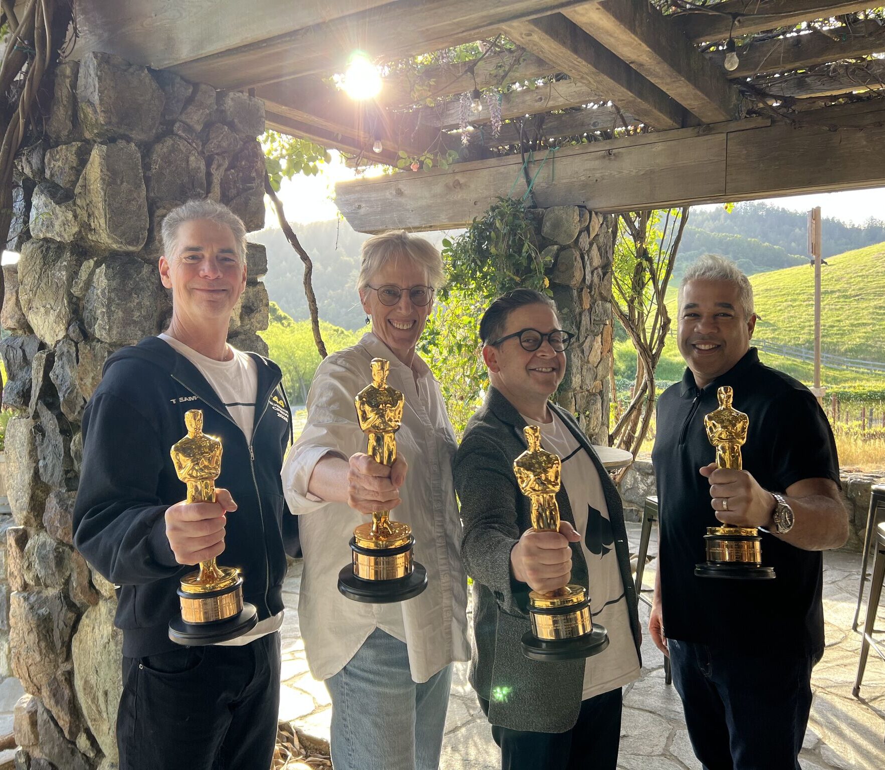 Skywalker Sound artists from F1: The Movie hold their Academy Award Oscar statues up to the camera.