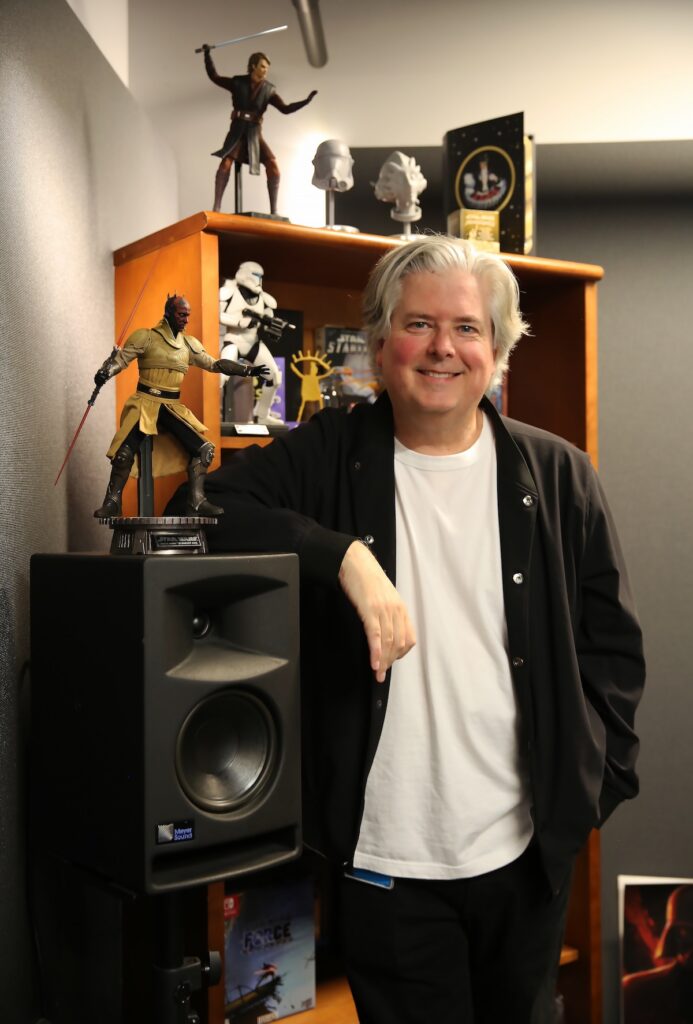 Skywalker Sound artist David W. Collins stands in his office with pieces of Star Wars decor.
